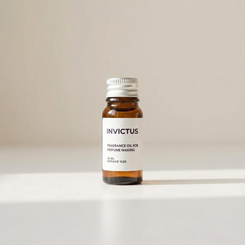 May include: A small, brown glass bottle with a silver cap. The label reads "Invictus, Fragrance Oil for Perfume Making, 10 ml, Dosage %20". The bottle is filled with a golden liquid.