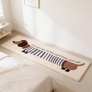 May include: A long, rectangular beige rug with a cartoon dachshund design. The dog wears a beret and a striped top. The dog's body is brown with blue stripes. Text on the rug reads, "Close your eyes and have a good dream, good night."
