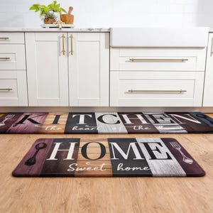 Könnte beinhalten: Zwei rechteckige Küchenmatten mit Holzoptik. Die obere Matte trägt die Aufschrift "KITCHEN the heart of the" in weißen Buchstaben. Die untere Matte trägt die Aufschrift "HOME Sweet home". Beide Matten haben ein Gabel- und Löffeldesign.