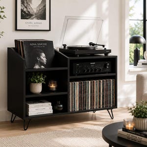 Puede incluir: Un mueble negro para tocadiscos con tocadiscos, amplificador y almacenamiento para discos de vinilo. El mueble tiene un diseño moderno de mediados de siglo con patas de horquilla. Una impresión enmarcada de Ansel Adams cuelga en la pared.
