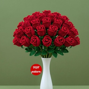Può includere: Un bouquet di rose rosse all'uncinetto in un vaso bianco. Le rose hanno steli e foglie verdi. Un cerchio rosso con il testo "PDF pattern" è visibile.