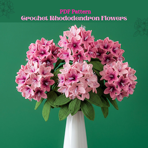 Può includere: Un modello PDF digitale intitolato Crochet Rhododendron Flowers che mostra un bouquet di fiori di rododendro all'uncinetto rosa con foglie verde scuro in un vaso bianco. I fiori hanno petali rosa chiaro, centri rosa scuro e stami bianchi.