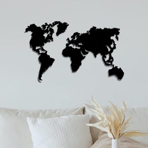 May include: A black wall-mounted world map silhouette featuring the distinct shapes of the continents. The design displays the landmasses of North and South America, Europe, Africa, Asia, and Australia in a solid, flat black finish.