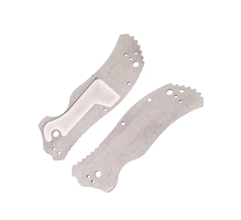 May include: Two silver-colored knife handle scales. One scale has a white insert and a curved shape with a serrated edge. The other scale is similar in shape and also has a serrated edge. Both have several small holes.