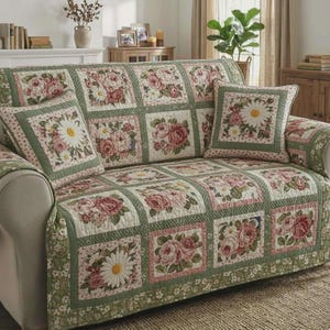 May include: A floral-patterned sofa cover and matching throw pillows. The cover features a patchwork design with squares of roses and daisies in pink, white, and green. The pillows have a daisy and rose design.