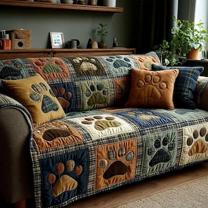 May include: A patchwork sofa cover and throw pillows featuring paw prints. The cover is made of squares in various colors, including blue, green, and brown, with a plaid pattern. The pillows are in solid colors with paw print appliqués.