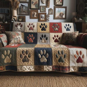 Könnte beinhalten: Eine Patchwork-Sofahusse mit großen Pfotenabdrücken in verschiedenen Farben, darunter Beige, Marineblau und Rot. Die Steppdecke hat einen rustikalen, ländlichen Stil. Dekorative Kissen mit Naturmustern ergänzen das Sofa.