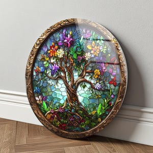 Könnte beinhalten: Ein rundes Buntglas-Kunstwerk mit einem Baum mit bunten Blumen und Schmetterlingen. Das Kunstwerk hat einen braunen, verzierten Rahmen und eine klare, glänzende Oberfläche. Die Äste und der Stamm des Baumes sind braun, der Hintergrund ist ein Mosaik aus blauem und grünem Glas.