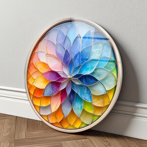 Peut inclure: Une œuvre d'art murale circulaire présentant un motif en forme de pétales superposés disposés en rayons. Les pétales présentent un dégradé de couleurs incluant le jaune, l'orange, le rose, le violet, le bleu et le vert, dans un cadre clair.