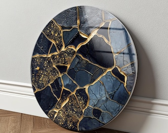 May include: A circular wall art piece with a glossy finish. The design features a mosaic of dark blue and grey fragments, with gold-coloured veins running through them. The artwork is mounted on a wall with a wooden floor.