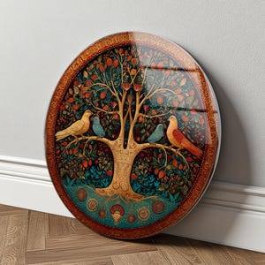 Peut inclure: Une plaque murale circulaire présentant une illustration détaillée d'un arbre central aux branches dorées, aux fruits rouges et au feuillage vert. Deux grands oiseaux et deux petits oiseaux bleus sont perchés sur les branches, encadrés par une bordure dorée.