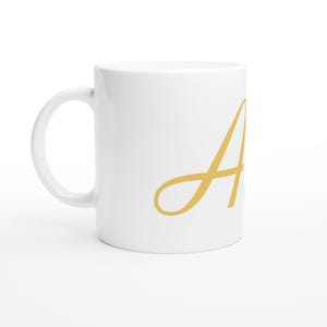 Peut inclure: Une tasse en céramique blanche avec la lettre "A" dorée en cursive. La tasse a une anse standard et une finition brillante. Le design est simple et élégant, adapté au café, au thé ou à d'autres boissons.
