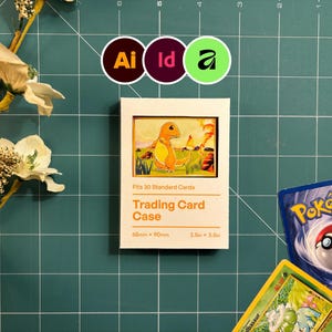 Op de afbeelding: Een witte trading card case met een Charmander illustratie, geschikt voor 30 standaard kaarten. De case meet 6,35 x 8,89 cm en heeft de tekst "Trading Card Case". Twee Pokémon kaarten zijn zichtbaar.