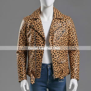 May include: A tan and black leopard print leather jacket with a classic biker style. The jacket features a notched collar, asymmetrical zipper closure, multiple pockets, and silver hardware. The jacket is displayed on a mannequin.
