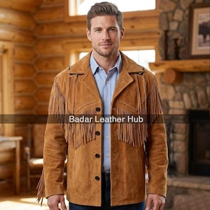 Puede incluir: Chaqueta de ante marrón con flecos, cierre de botones y cuello con solapas. La chaqueta se lleva sobre una camisa abotonada azul claro. El texto "Badar Leather Hub" es visible.