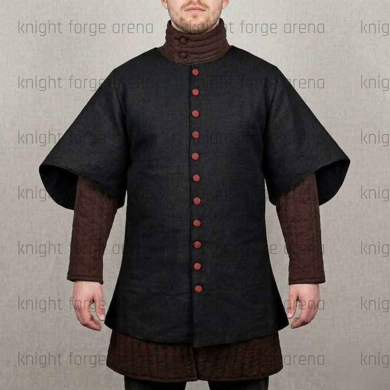 May include: Black medieval gambeson with red buttons and short sleeves. The garment has a high collar and is worn over a brown undergarment. The text "knight forge arena" is visible on the image.