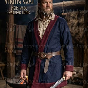 May include: A navy blue Viking coat with burgundy trim, a brown leather belt, and a decorative buckle. The coat has long sleeves and is made of wool. The image also shows a sword and the text "KLAPPENROCK VIKING COAT".