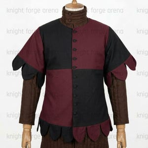 Peut inclure: Un pourpoint pr&eacute;sentant un corsage &eacute;cartel&eacute; noir et bordeaux avec une fermeture boutonn&eacute;e sur le devant. Le v&ecirc;tement comprend des manches longues matelass&eacute;es marron et un col haut matelass&eacute; marron. L'ourlet et les poignets sont festonn&eacute;s.