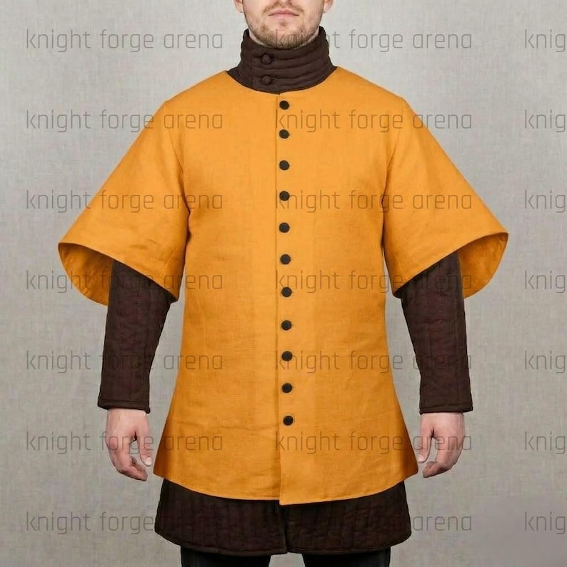 May include: Mustard yellow medieval tunic with black buttons and wide sleeves. The tunic has a high collar and is worn over brown quilted sleeves and a matching skirt. The text "knight forge arena" is visible.