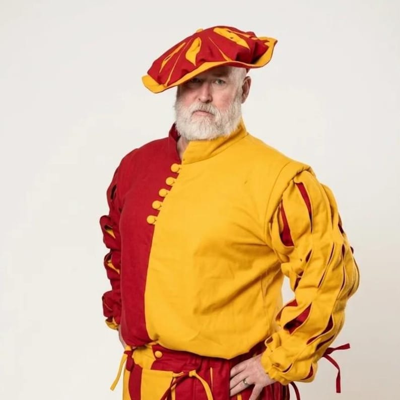 Peut inclure: Un pourpoint rouge et jaune dot&eacute; d'un col montant, d'une fermeture lat&eacute;rale &agrave; boutons et de manches longues avec des fentes verticales r&eacute;v&eacute;lant une doublure rouge. La tenue comprend un b&eacute;ret assorti rouge et jaune et un pantalon rouge.