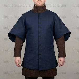 May include: A navy blue medieval tunic with a button-up front and short, wide sleeves. The tunic is layered over a brown, high-collared shirt and a quilted brown skirt. The image is of a person wearing the tunic.