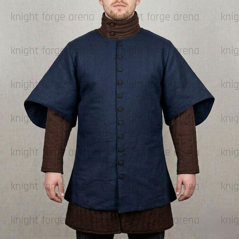 May include: A navy blue medieval tunic with a button-up front and short, wide sleeves. The tunic is layered over a brown, high-collared shirt and a quilted brown skirt. The image is of a person wearing the tunic.