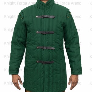 May include: A forest green padded jacket with a high collar and long sleeves. The jacket features three black leather straps with buckles down the front and decorative stitching. The shoulders have small metal accents. The jacket is designed for protection.