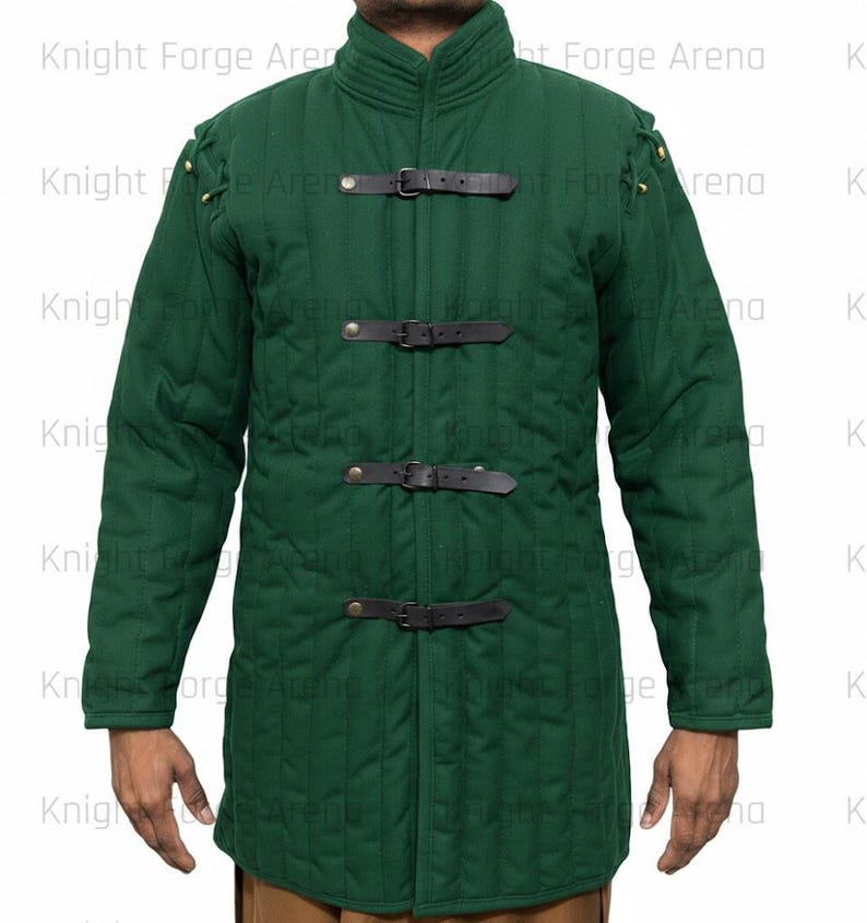 May include: A forest green padded jacket with a high collar and long sleeves. The jacket features three black leather straps with buckles down the front and decorative stitching. The shoulders have small metal accents. The jacket is designed for protection.