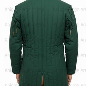 May include: A dark green quilted jacket with a high collar and long sleeves. The jacket has vertical stitching and decorative ties on the shoulders and sleeves. The back of the jacket is visible, with a split at the bottom. The text "Knight Forge Arena" is visible.