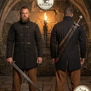 May include: Two men wearing black quilted jackets and brown pants stand in a stone archway. One holds a sword. The jackets have leather straps. The image includes a circular logo with a knight on a horse and the text "KNIGHT FORGE ARENA".