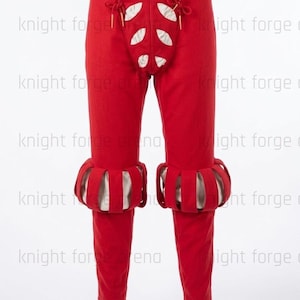 May include: Red historical pants with decorative cutouts and ruffled cuffs. The pants have a high waist and are made of a solid red fabric. The cuffs are white and red. The pants are part of a historical costume.
