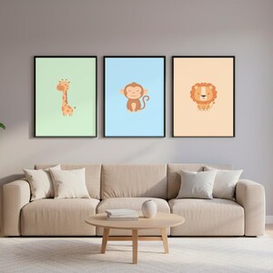 Puede incluir: Tres láminas enmarcadas con animales. Las láminas presentan una jirafa, un mono y un león sobre fondos pastel. La jirafa está sobre un fondo verde claro, el mono sobre un azul claro y el león sobre un fondo melocotón.
