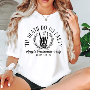 Puede incluir: Camiseta blanca con un gr&aacute;fico negro que dice "Til Death Do Us Party" con una mano de esqueleto haciendo un signo de rock and roll y un coraz&oacute;n. El texto "Avery's Bachelorette Party Nashville, TN" est&aacute; debajo del gr&aacute;fico.