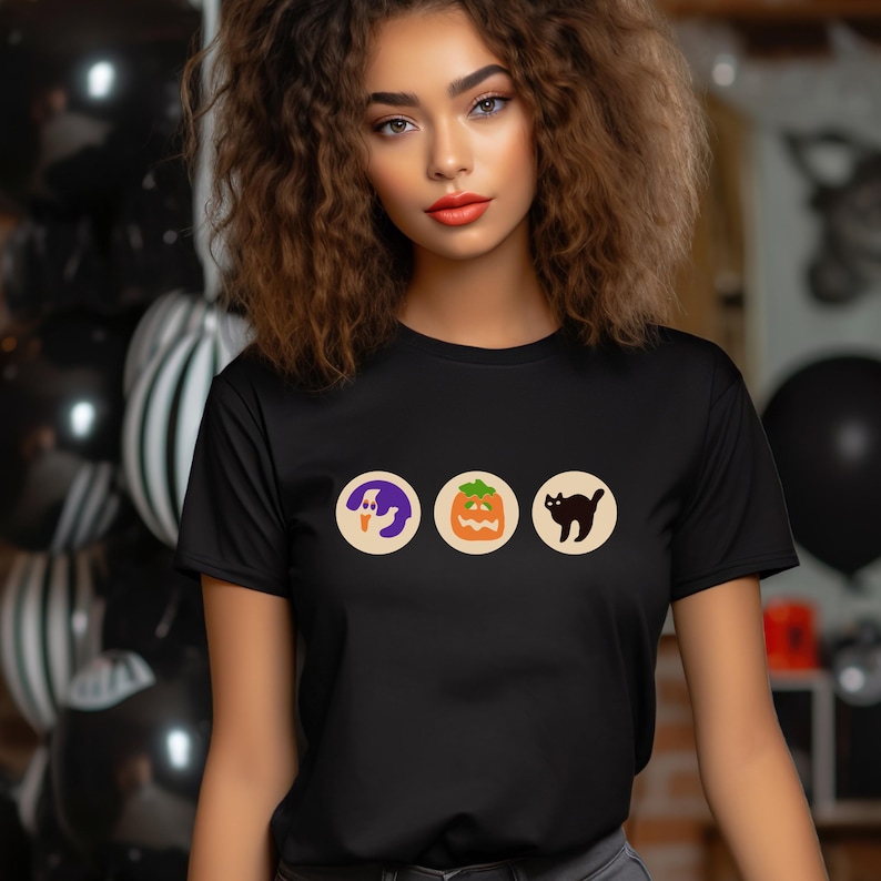 May include: A black t-shirt featuring a graphic of three Halloween icons: a ghost, a jack-o'-lantern, and a black cat.