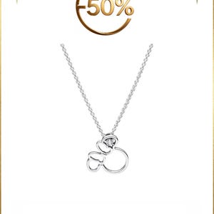 Op de afbeelding: Een zilverkleurige ketting met een hanger in de vorm van een gestileerde muizenkop met een strik, geaccentueerd door een kleine heldere steen. Boven de hanger toont een goudkleurige cirkelvormige afbeelding de tekst -50% op een witte achtergrond.
