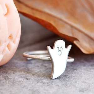 Op de afbeelding: Een zilveren ring met een spookbedel. Het spook heeft twee kleine cirkels voor ogen en een kleine cirkel voor een mond.