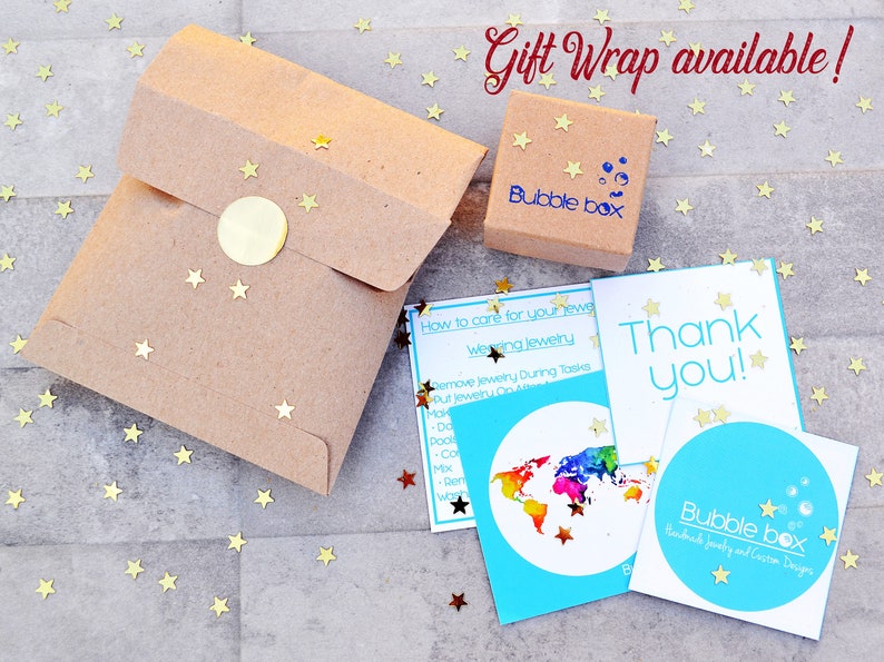 May include: A brown paper gift bag with a gold sticker and a small brown box with the text "Bubble Box" on it. The image also includes a blue card with the text "Thank you!" and a world map with rainbow colors. The text "Gift Wrap available!" is written in red at the top of the image.