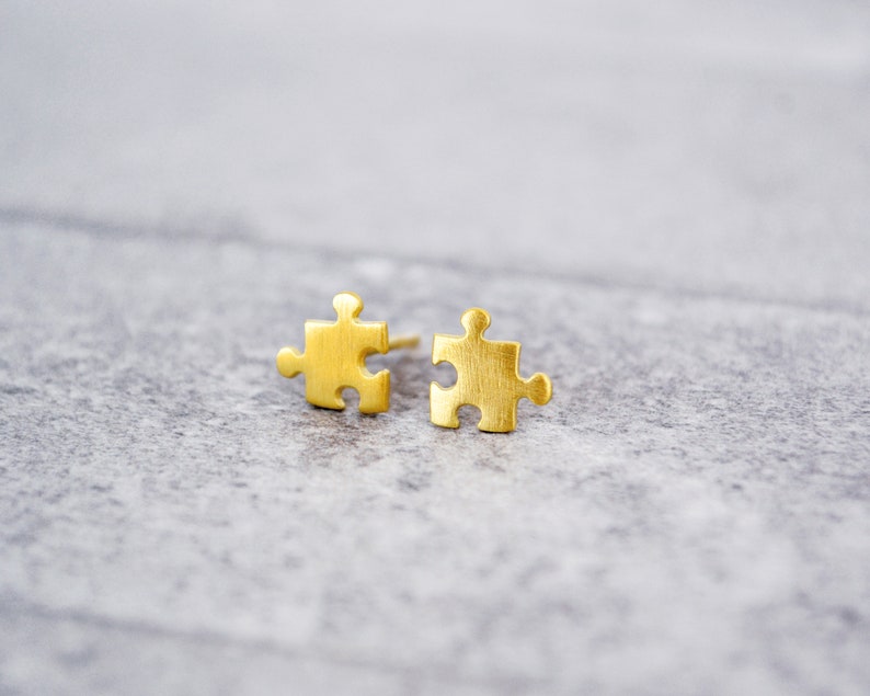 May include: A pair of gold-toned puzzle piece shaped stud earrings.