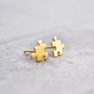 May include: A pair of gold-toned puzzle piece earrings. The earrings are small and delicate, and they are perfect for adding a touch of whimsy to any outfit.