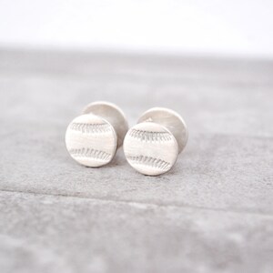 May include: A pair of silver cufflinks with a baseball design.