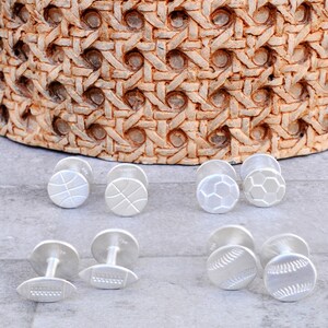 May include: Six pairs of silver cufflinks with different sports designs: basketball, soccer, football, and baseball.