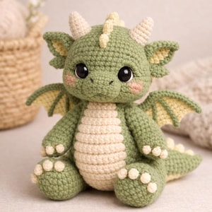 Puede incluir: Un drag&oacute;n de ganchillo hecho a mano en tonos verdes y crema. El peluche tiene grandes ojos negros, peque&ntilde;os cuernos y alas. El drag&oacute;n est&aacute; sentado, mostrando su vientre y pies color crema. Una criatura encantadora y caprichosa.
