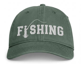 May include: A dark green baseball cap featuring white embroidered text that reads FISHING, with the letter I replaced by a graphic of a person holding a fishing rod and line, creating a cohesive design on the front of the six-panel hat.