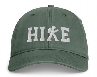 May include: A dark green baseball cap featuring white embroidered text that reads HIKE, with the letter K replaced by a white stick figure icon of a person wearing a backpack and walking with a trekking pole, centered on the front panel.