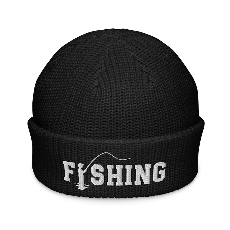 May include: A black knit beanie with a cuffed brim featuring white embroidered text that reads FISHING, with the letter I replaced by a graphic of a person holding a fishing rod and line extending over the remaining letters.