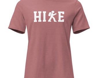 May include: A dusty rose short-sleeved crew neck t-shirt featuring the white text HIKE printed across the chest, with the letter K replaced by a white graphic icon of a person wearing a backpack and walking forward.