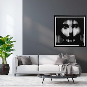 May include: A square black and white wall art piece featuring a stylized portrait of a person with a beard, rendered in vertical lines that create a high-contrast effect. The artwork is framed in a thin black border and displayed on a dark gray wall.