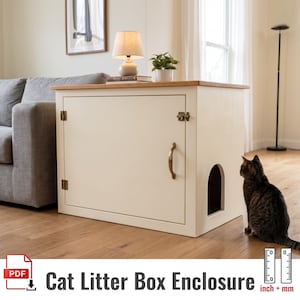 May include: A cream-colored wooden cat litter box enclosure featuring a rectangular top surface, a front-hinged door with a brass handle and latch, and an arched side entry. The unit sits on a wooden floor next to a gray sofa.
