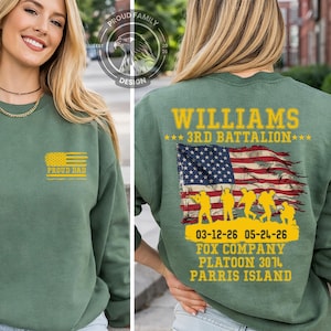 May include: Green sweatshirt with "PROUD DAD" and a yellow American flag graphic on the front. The back features "WILLIAMS 3RD BATTALION" with an American flag and soldier silhouettes. Dates and unit information are also printed.