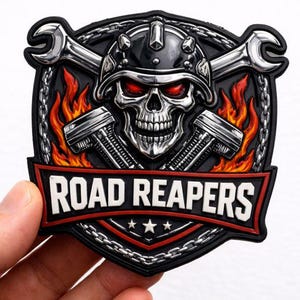 May include: A black and silver patch featuring a skull wearing a helmet with red eyes, crossed wrenches, and pistons. The patch has the words "ROAD REAPERS" in white on a red banner, with a chain border and flames.